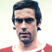 Ein männlicher Fußballspieler mit kurzem Haar und einem sportlichen Trikot in Rot und Weiß blickt direkt in die Kamera.